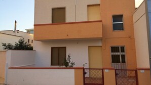 Un bâtiment à deux étages, doté d’une façade sobre, d’un balcon à l’étage supérieur et d’une entrée fermée par un portail.