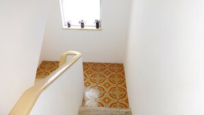 Un escalier muni d’une rampe menant à une fenêtre ornée de trois petits bouquets de fleurs.