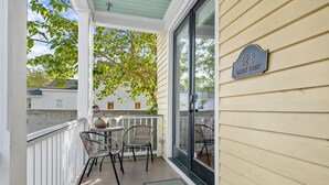 A covered porch with two wicker chairs and a small table, a glass door, and a street sign reading "52-B CANYON STREET".