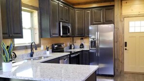 A modern kitchen with dark cabinets, stainless steel appliances, and a granite countertop.