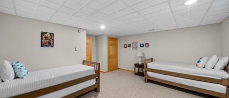 A room with two single beds, a small table, and a door leading to another room.
