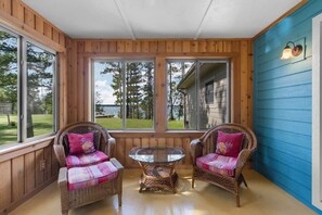 A room with two wicker chairs, a glass table, and large windows. - Sunset View | Superior West Twin Lake Home (Lewiston)