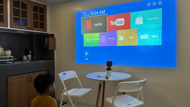 A projection of a smart TV interface with various app icons, including Netflix and YouTube, in a modern room with a dining table and chairs. - Cozy Familia Apartment Studio Type (Cagayan de Oro City)