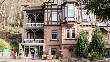 A Victorian-style building with a balcony, large windows, and a stone facade.