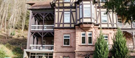 A Victorian-style building with a balcony, large windows, and a stone facade.