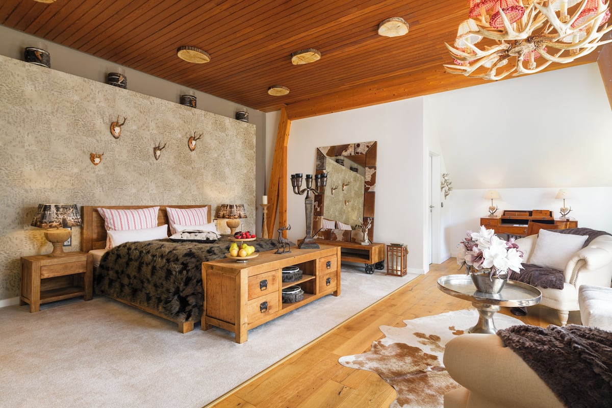 A bedroom with a wooden bed, a wooden dresser, a mirror, and a chandelier.