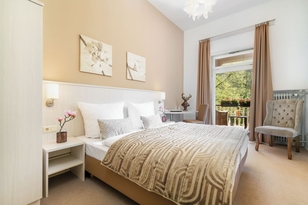 A bedroom with a bed, bedside tables, a chair, and artwork on the wall.