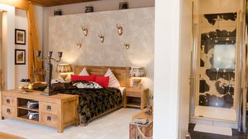 A bedroom with a bed, bedside tables, a wooden dresser, and a wall-mounted shelf.