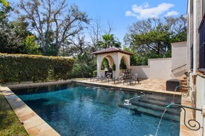 Une piscine dotée d’une pergola et de chaises longues.