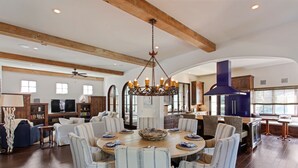 A spacious living room with a large round table, comfortable seating, and a modern fireplace.