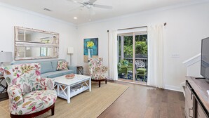 A spacious living room with a sofa, two armchairs, a coffee table, and a television. - 601 Mariners Circle by Hodnett Cooper (St. Simons Island)