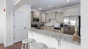 A modern kitchen with white cabinetry, stainless steel appliances, and a granite countertop. - 601 Mariners Circle by Hodnett Cooper (St. Simons Island)