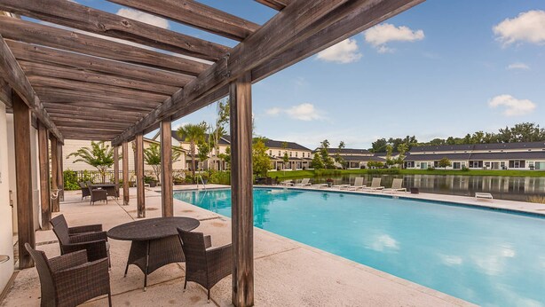 A covered outdoor area with a pool, lounge chairs, and a table. - 601 Mariners Circle by Hodnett Cooper (St. Simons Island)