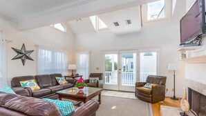 A spacious living room with a fireplace, leather sofas, a coffee table, and a star decoration on the wall. - 22 Coast Cottages by Hodnett Cooper (St. Simons Island)