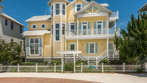 A multi-story yellow building with white railings and a white picket fence. - 22 Coast Cottages by Hodnett Cooper (St. Simons Island)