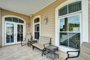 A covered patio with a bench, a small table, and a large window.
