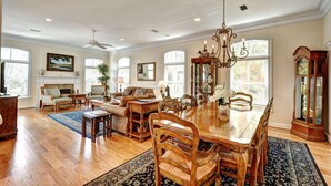A spacious living room with a large wooden dining table, comfortable seating, and a fireplace. - 2225 Bruce Drive by Hodnett Cooper (St. Simons Island)