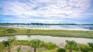 A marina with numerous boats docked, surrounded by grassy areas and palm trees.