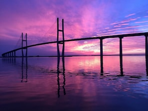 A bridge with a clear view of its structure and cables, spanning over a body of water. - 647 Demere Way by Hodnett Cooper (St. Simons Island)