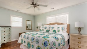 A bedroom with a bed, dresser, nightstand, and ceiling fan.