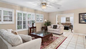 A living room with a beige sofa, a glass coffee table, and a red patterned rug. - 11908 Old Demere Rd by Hodnett Cooper (St. Simons Island)
