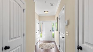 A hallway with white doors, a round rug, and a ceiling light. - 1203 Reserve Lane by Hodnett Cooper (St. Simons Island)