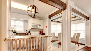 A kitchen with a wooden island, white cabinets, and a hanging light fixture.