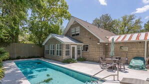 A backyard with a swimming pool, patio furniture, and a covered barbecue area. - 4316 7th Street by Hodnett Cooper (St. Simons Island)