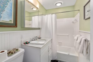 A bathroom with a white sink, mirror, and bathtub.
