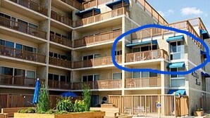 Un edificio residencial de varios pisos con balcones, jardineras de madera y cielo despejado.