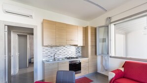 Eine kleine Küche mit Holzschränken, einer gefliesten Spritzschutzwand und einem roten Sofa.