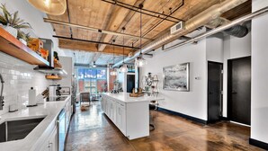 A modern kitchen with white cabinetry, a central island, and exposed ductwork on the ceiling. - Urban Oasis In Downtown Waco; short walk to Silos (Waco)