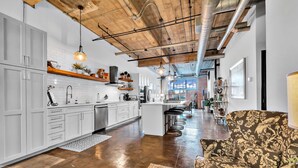 A modern kitchen with white cabinets, a central island, and hanging pendant lights. - Urban Oasis In Downtown Waco; short walk to Silos (Waco)