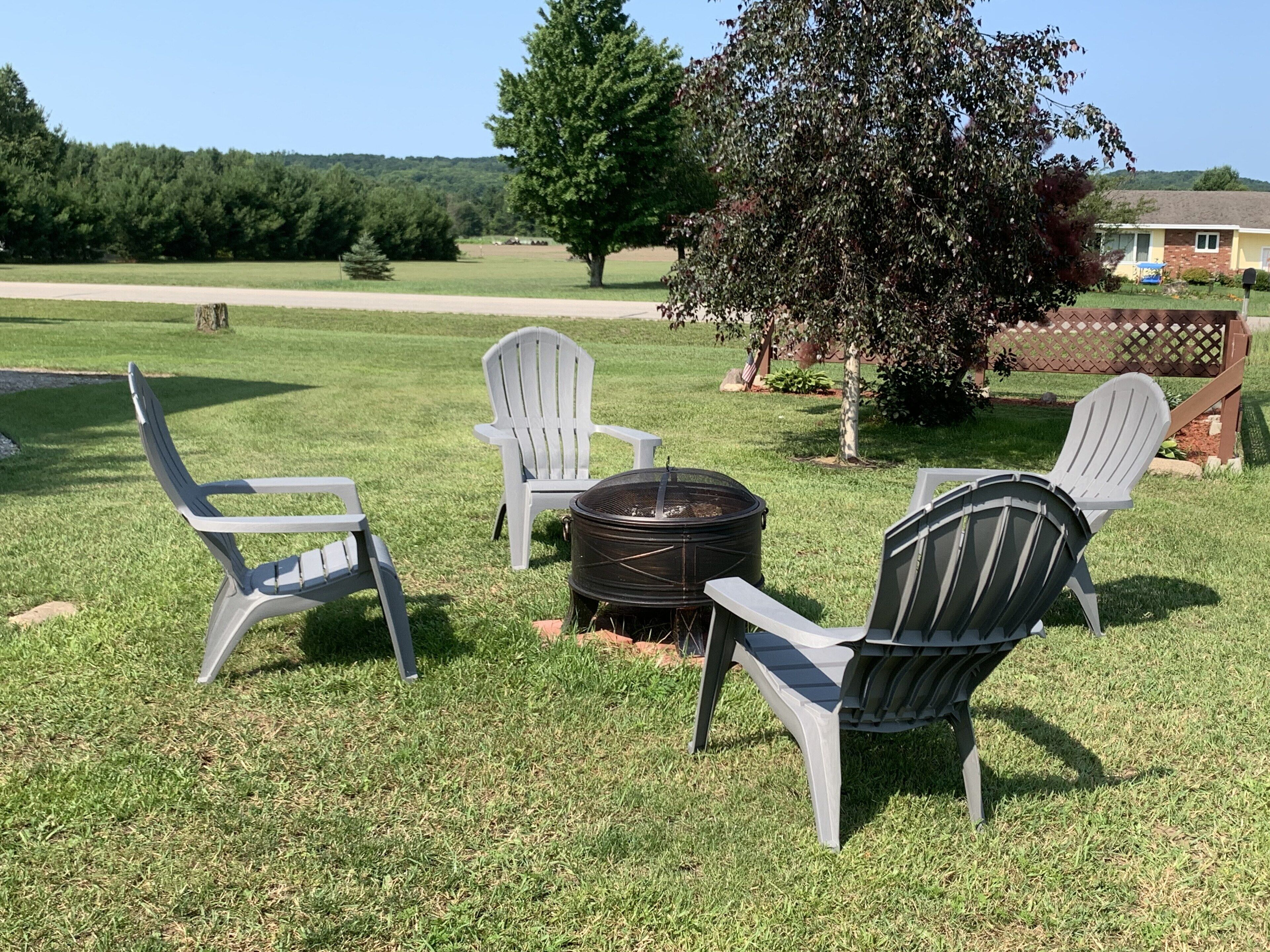 A grassy outdoor area with Adirondack chairs and a fire pit.
