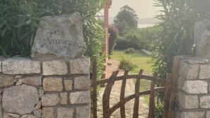 Un muro de piedra con un letrero que dice "Casa Vittoria" que da a un portón de madera.