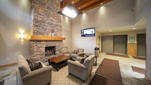 Una sala de estar con chimenea de piedra, sofás, una mesa de centro y un televisor de pantalla plana montado en la pared.