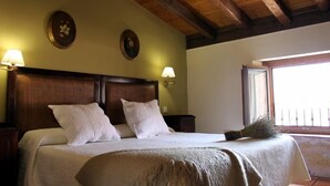 Ein Schlafzimmer mit einem hölzernen Kopfteil, zwei Nachttischlampen und einem Fenster mit Blick.