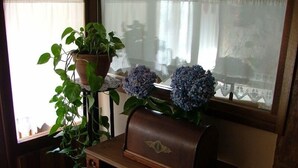 Eine Holzbank mit einem Ledermailkasten und einem Topf mit Hortensienblüten.