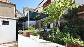 A narrow street with buildings on either side, potted plants, and a clear blue sky. - Apartment Varos 1 (Primosten)