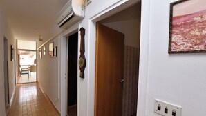 A hallway with a tiled floor, a wooden door, a wall-mounted clock, and a framed picture. - Apartment Varos 1 (Primosten)