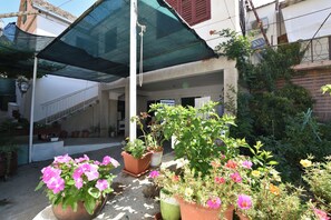 A covered outdoor area with potted plants and a staircase leading to a building.