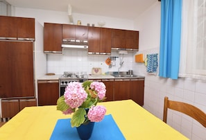 A kitchen with wooden cabinets, a stove, and a dining table with a blue placemat.