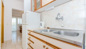 A modern kitchen with a double sink, wooden cabinetry, and a built-in oven. - Apartments Zoric (Rogoznica)