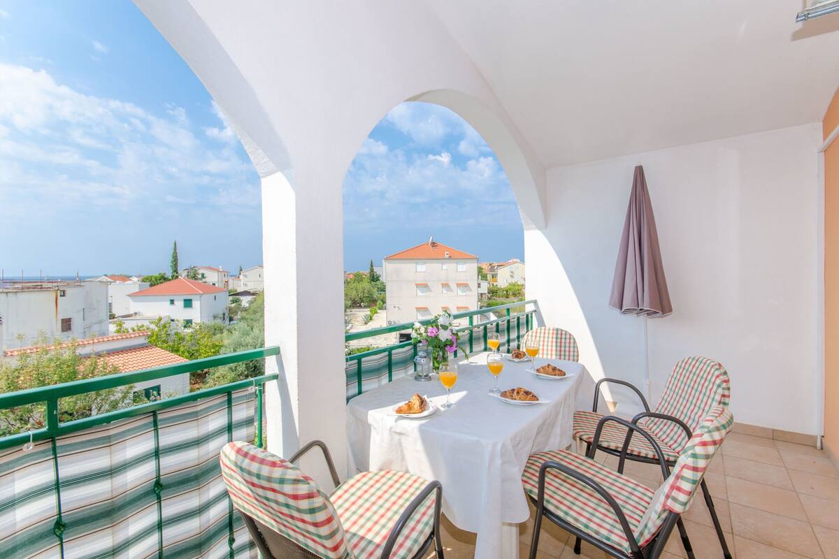 A balcony with a table set for two, chairs, and a view of buildings in the background.