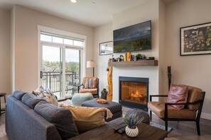A living room with a fireplace, a sofa, a chair, and a television on the wall.