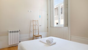 A hotel room with a bed, a radiator, a wooden ladder, a window, and a door. - Best Guest Porto Hostel (Porto)