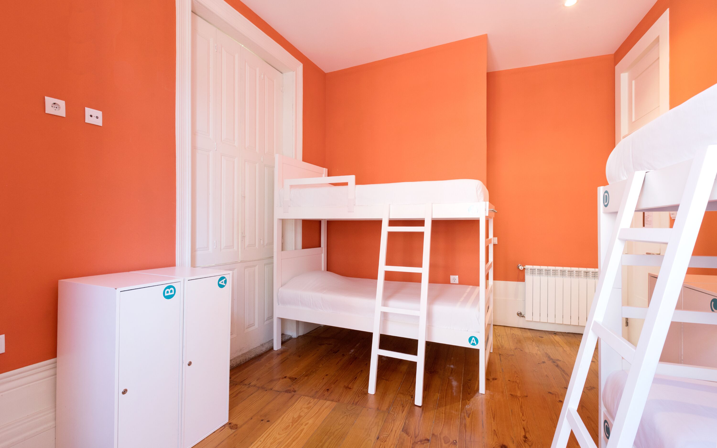 Una habitación con dos literas, un radiador blanco y un armario blanco con puerta.