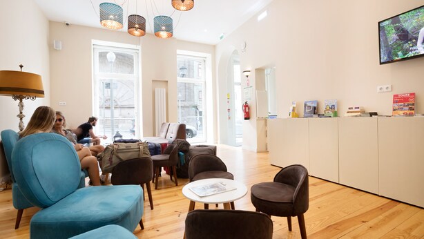 A modern lobby with seating areas, a reception desk, and a television screen. - Best Guest Porto Hostel (Porto)