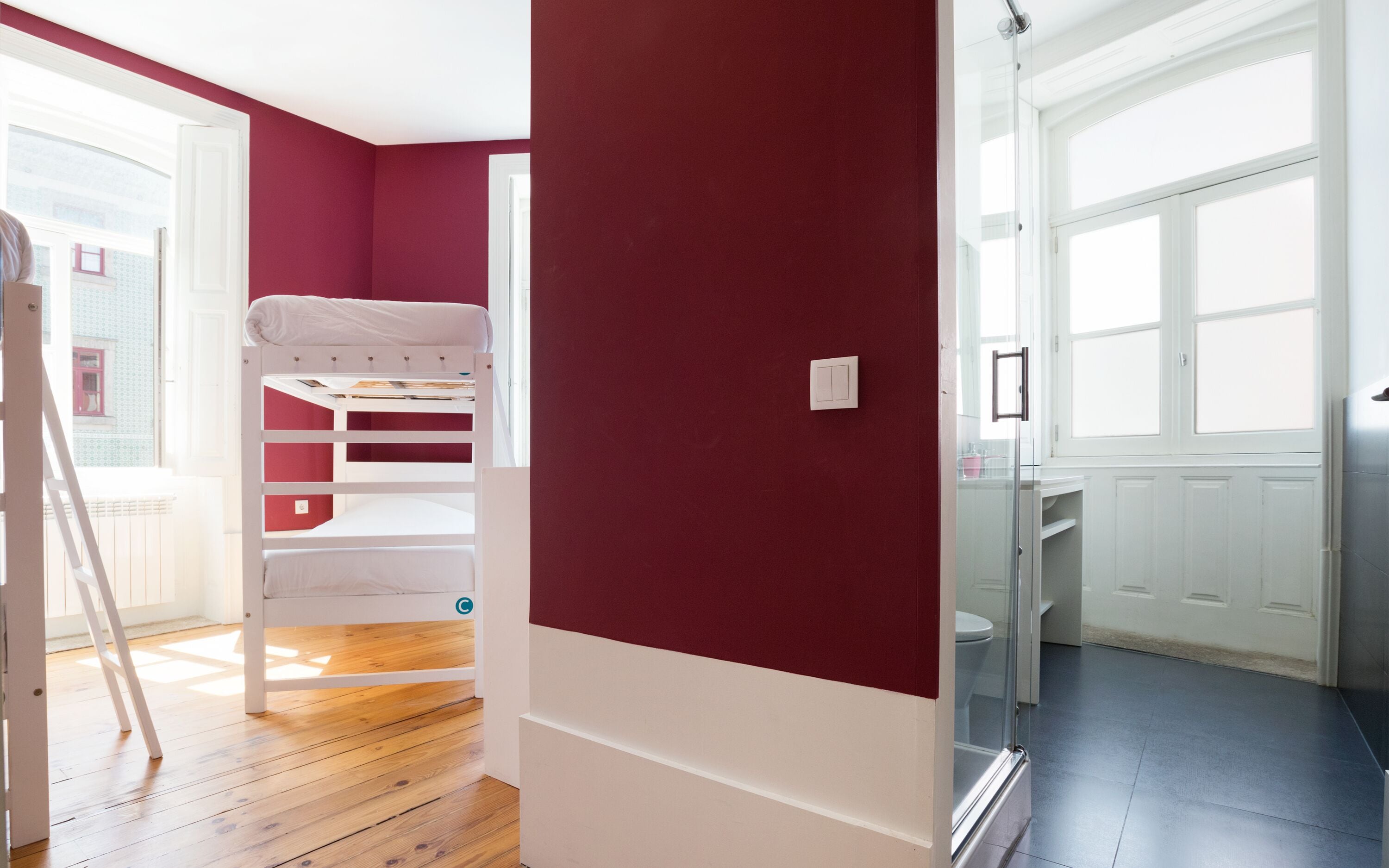 A room with a bunk bed, a radiator, a white door, and a window.