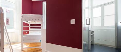 A room with a bunk bed, a radiator, a white door, and a window.